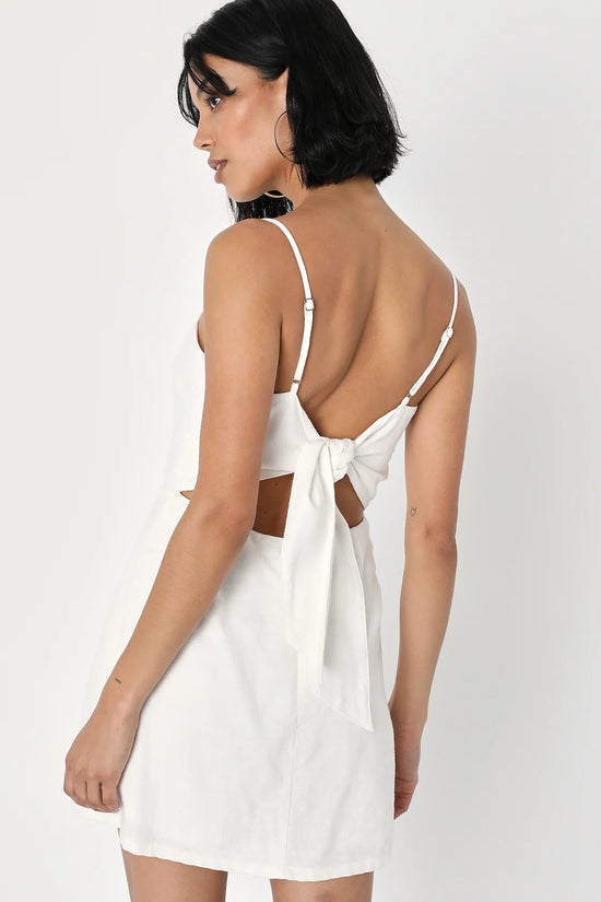 Back view of a woman wearing a Ivory Tie-Back Cutout Skort Romper by LuLu's