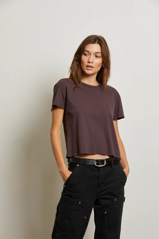 
                      
                        A woman wearing a brownish purple short sleeve t-shirt with black jeans
                      
                    
