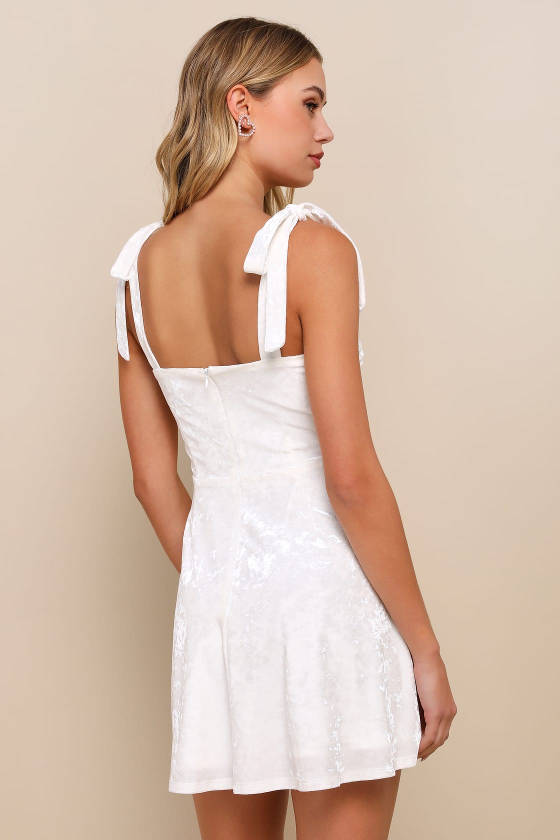 Back view of a woman wearing a White Crushed Velvet Tie-Strap Mini Dress