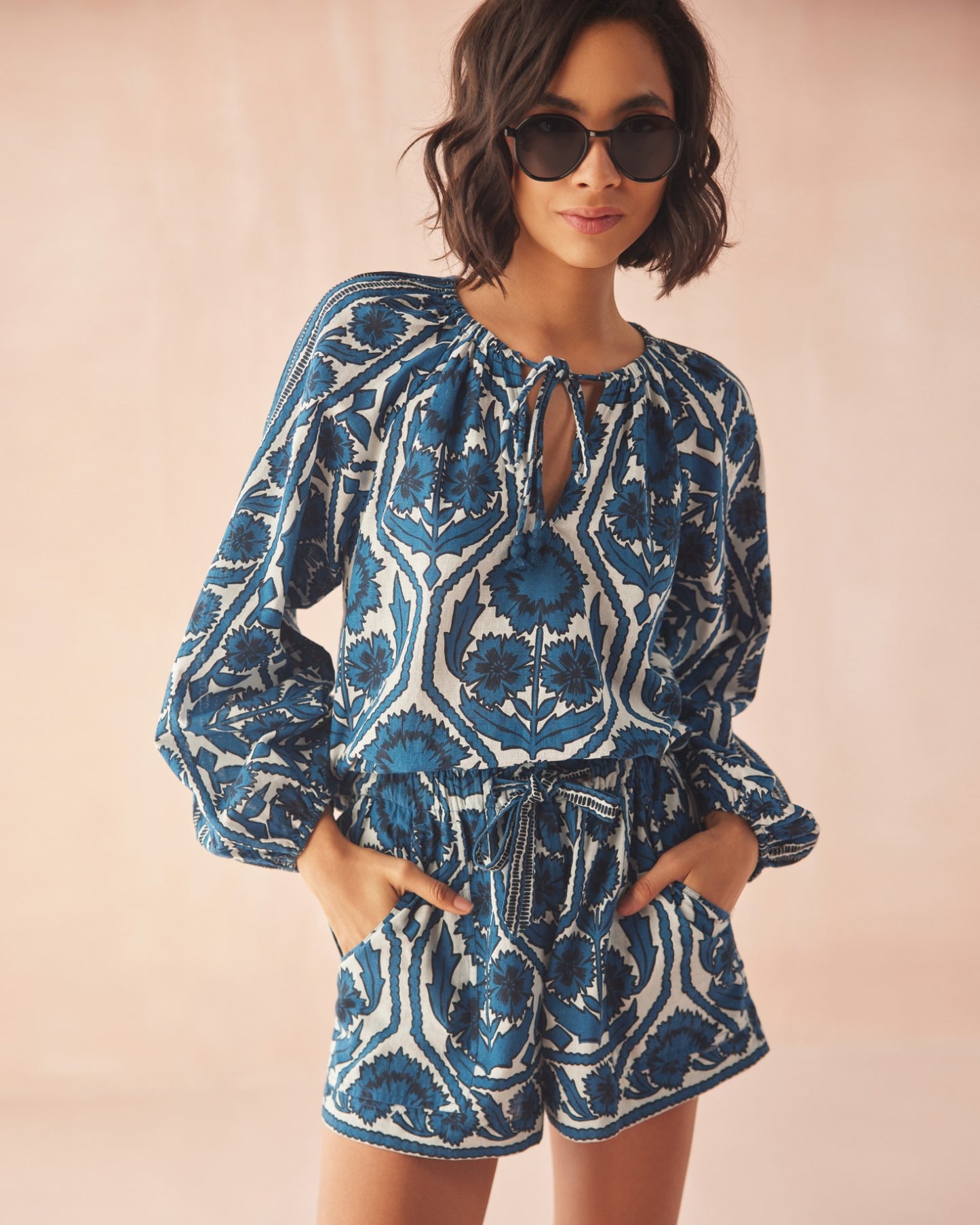 Woman wearing a blue and white patterned outfit  from OMIKA with sunglasses 