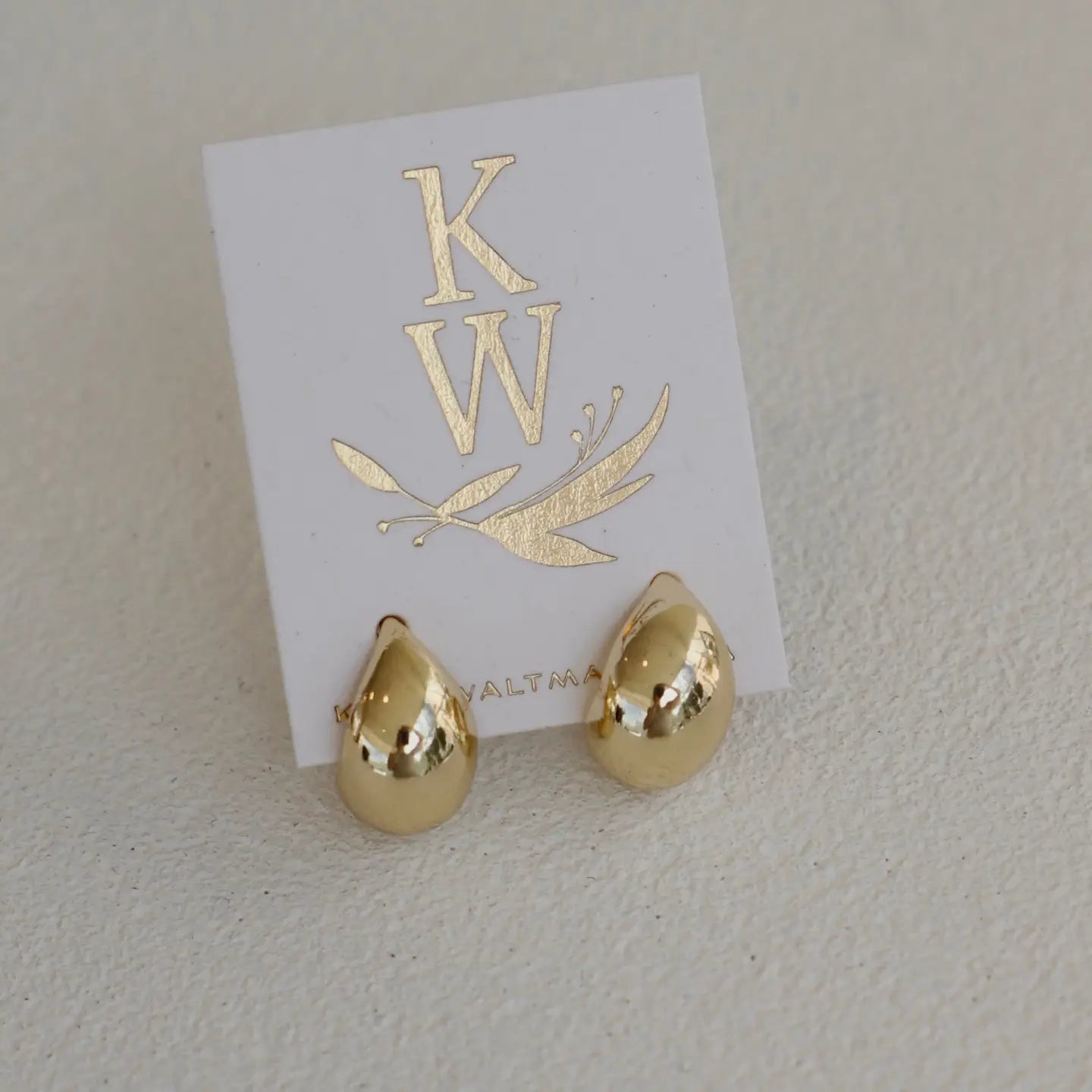 Gold dome stud earrings on a white card with 'KW' branding.