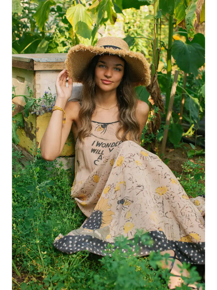 
                      
                        A woman sitting in a field while wearing the Milk & Honey Bohéme Slip Dress by Market of Stars
                      
                    