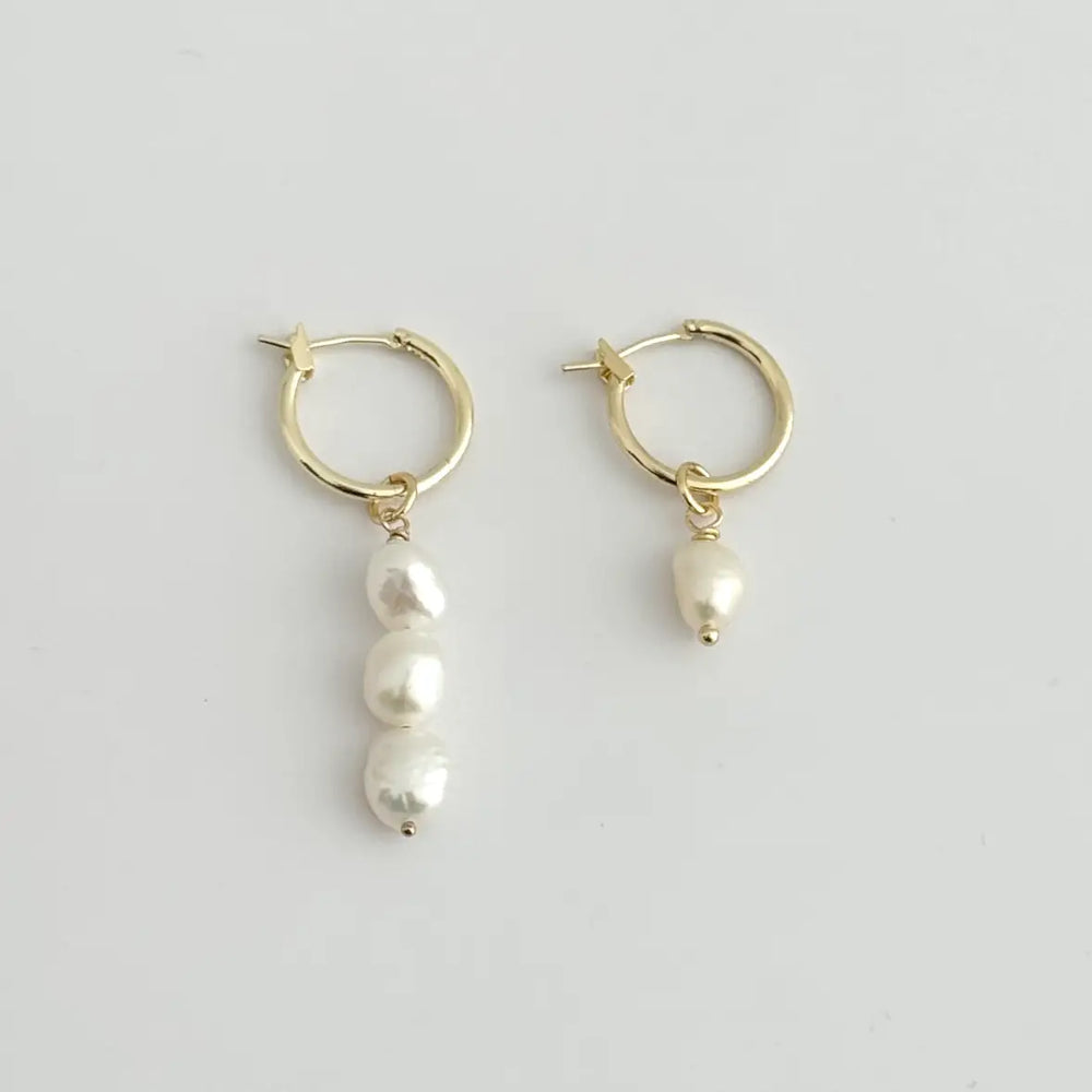 The Leva Mismatched Hoops by Tramps + Thieves are 18K GoldFilled Hoop Earrings with freshwater pearl charms, and are available to shop at Harbour Thread in Burlington, VT. 