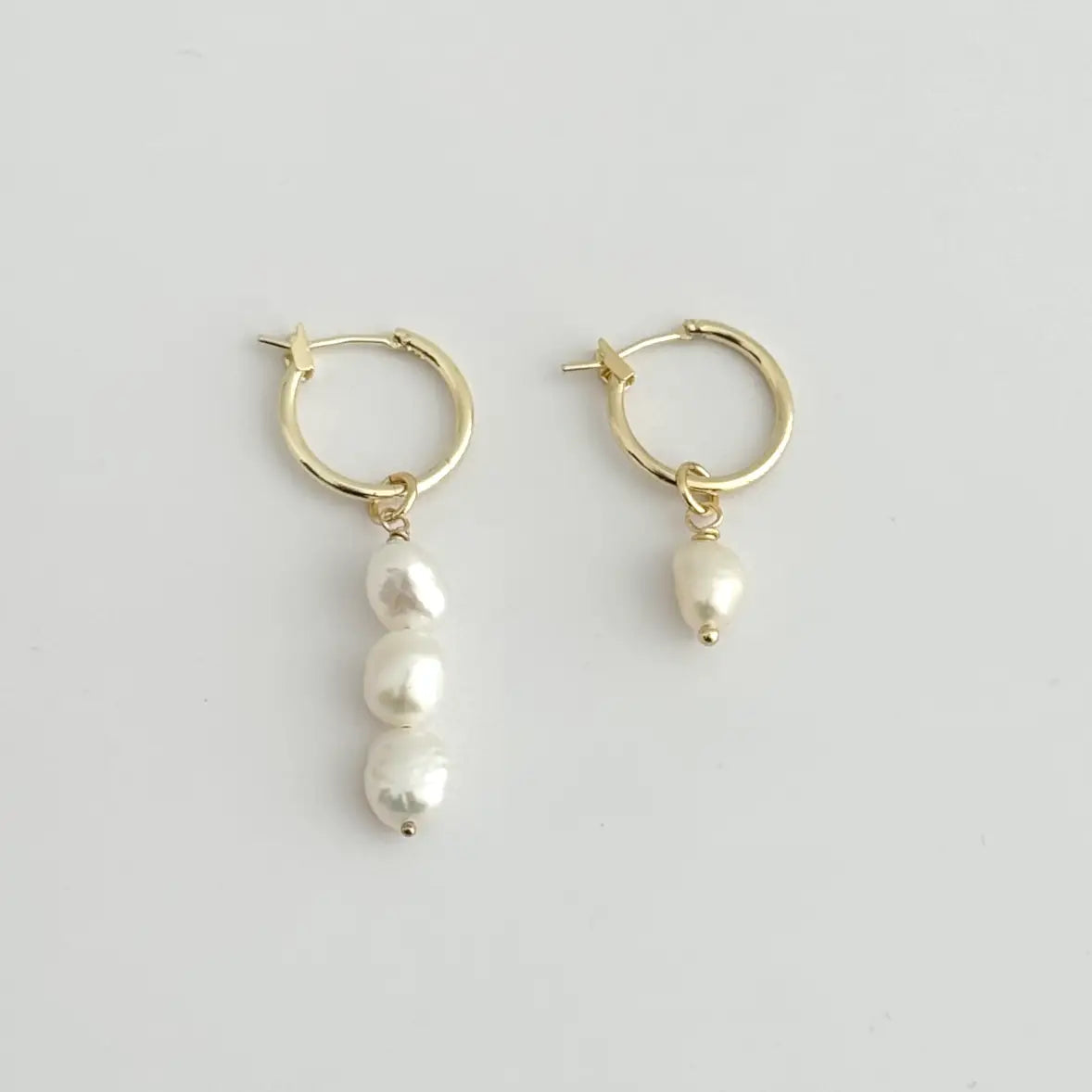 The Leva Mismatched Hoops by Tramps + Thieves are 18K GoldFilled Hoop Earrings with freshwater pearl charms, and are available to shop at Harbour Thread in Burlington, VT. 