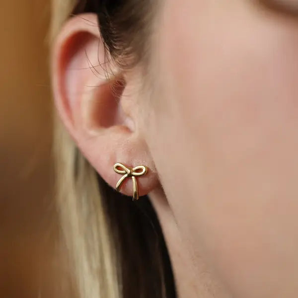 Woman wearing the Gold Dainty Bow Stud Earrings by The Land Of Salt