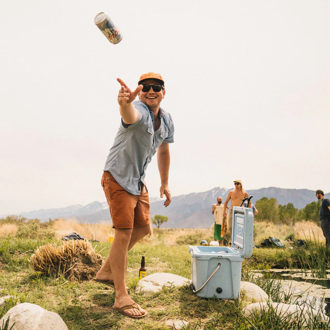 A man at an outside picnic wearing the Faded Blue Oxford H Bar B Snapshirt  by Howler Bros