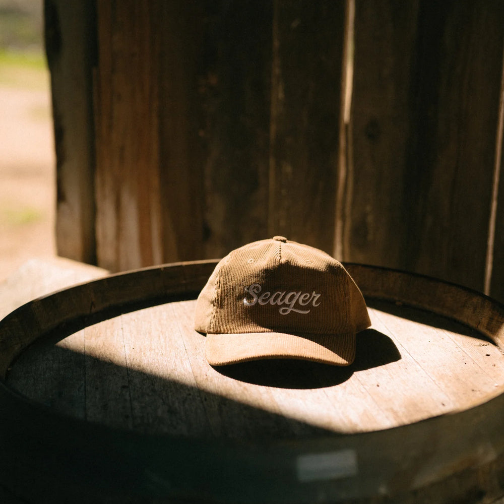 
                      
                        The Big Khak Corduroy Snapback Hat by the brand Seager styled on top of a barrel 
                      
                    