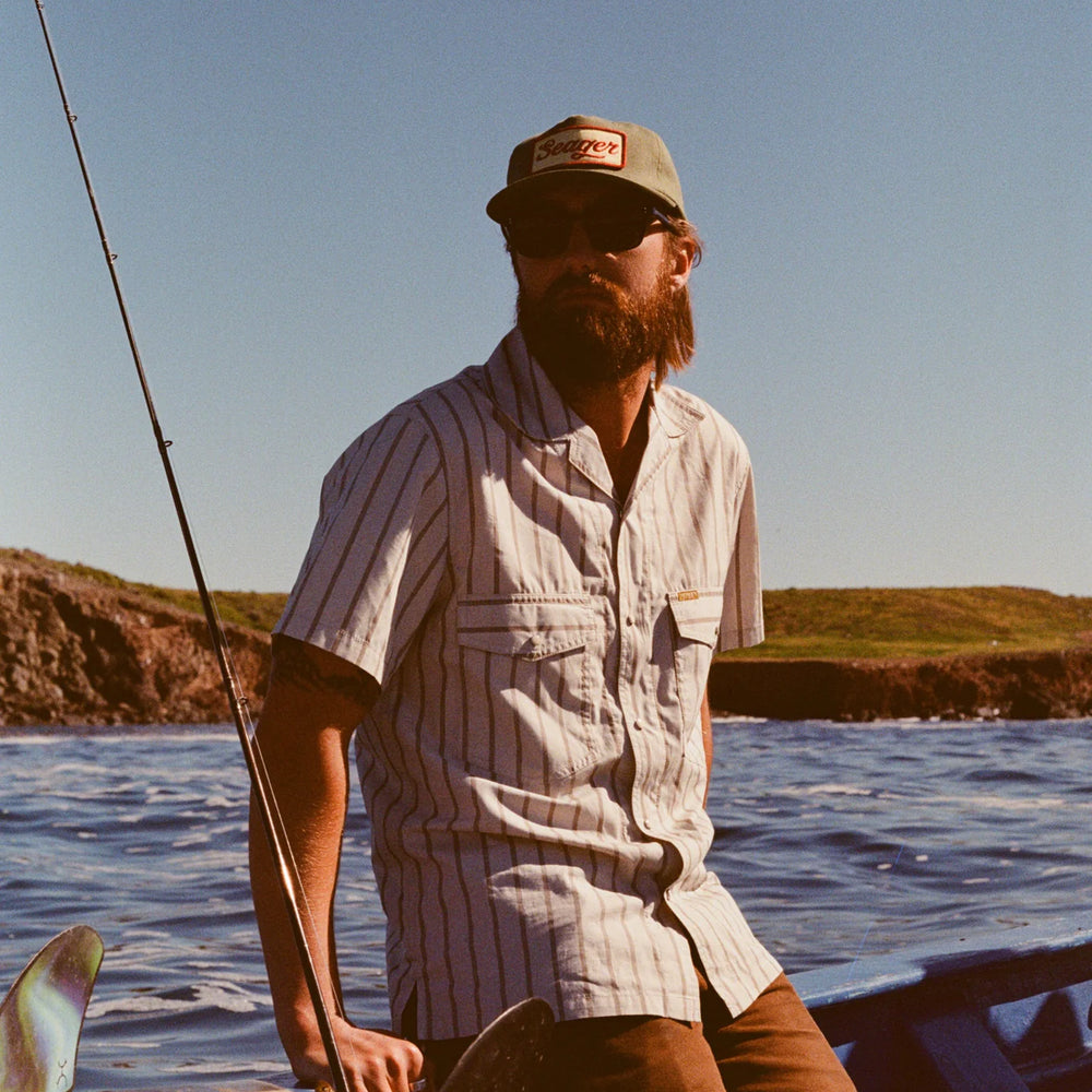 
                      
                        A man sitting on a boat fishing. He's wearing the Green Uncle Bill Hemp Snapback Hat by the brand Seager as a part of his outfit. 
                      
                    