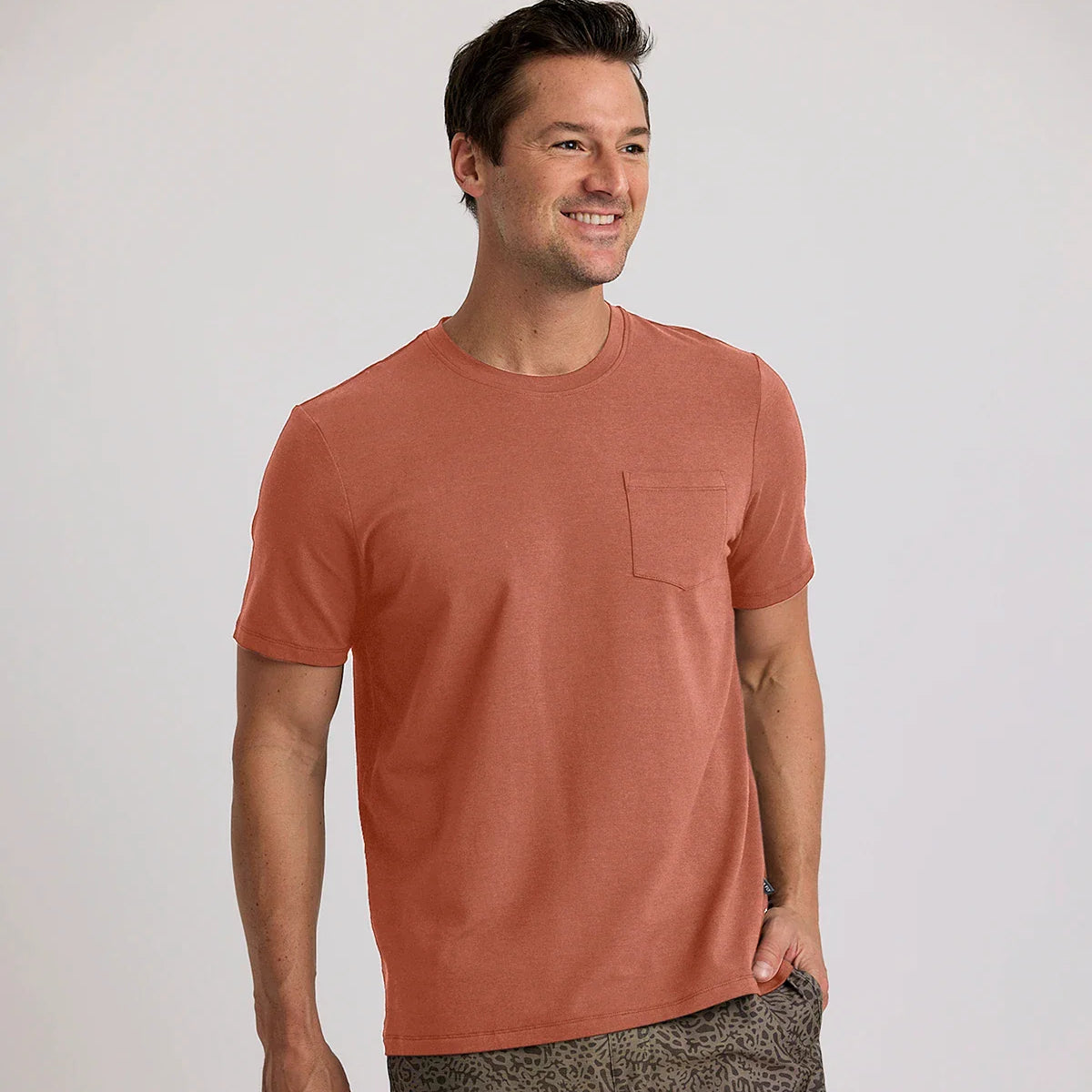 A man wearing the Men's Bamboo Current Pocket Tee by Free Fly in the color Redwood