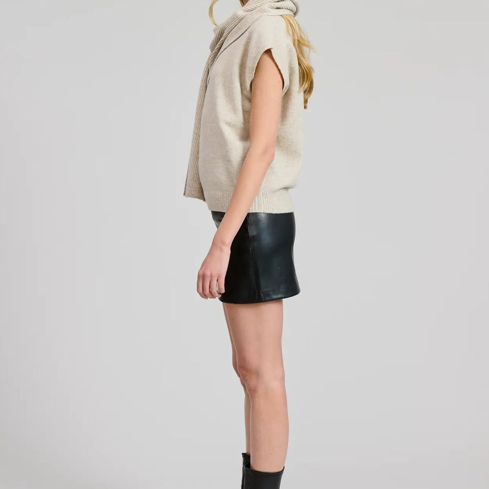 Woman wearing a beige sweater top with a black mini skirt and black boots