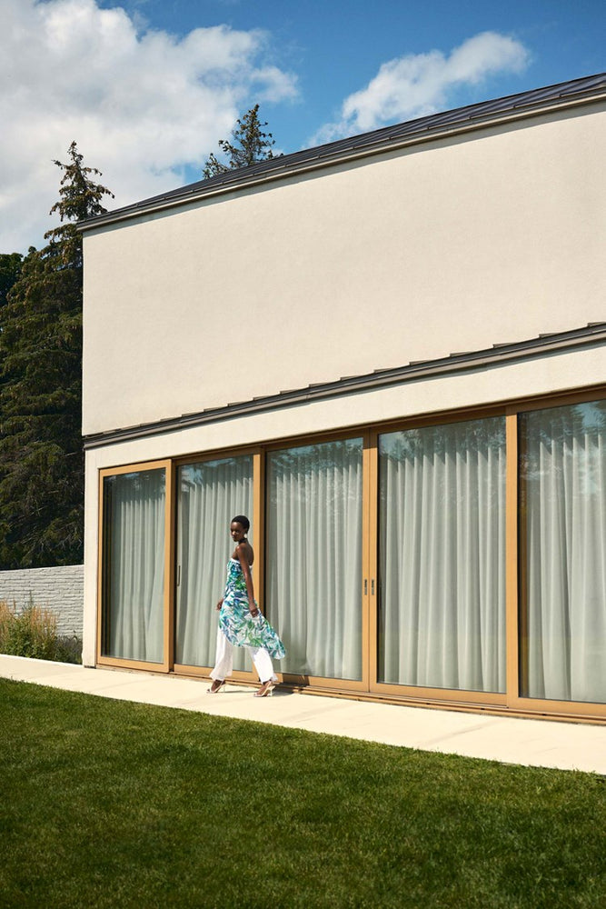 
                      
                        woman wearing the view of the Joseph Ribkoff Tropical Print Jumpsuit while walking by a building
                      
                    