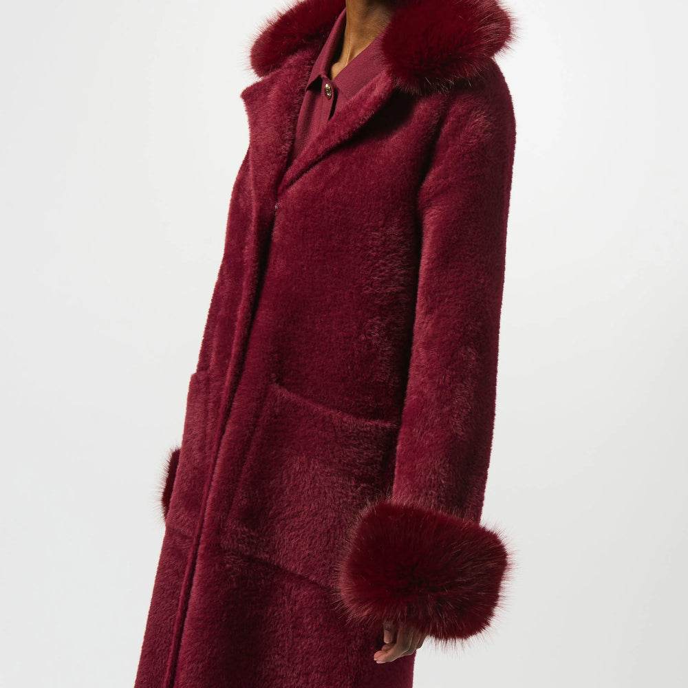 Woman wearing a burgundy coat with fur trim on a white background
