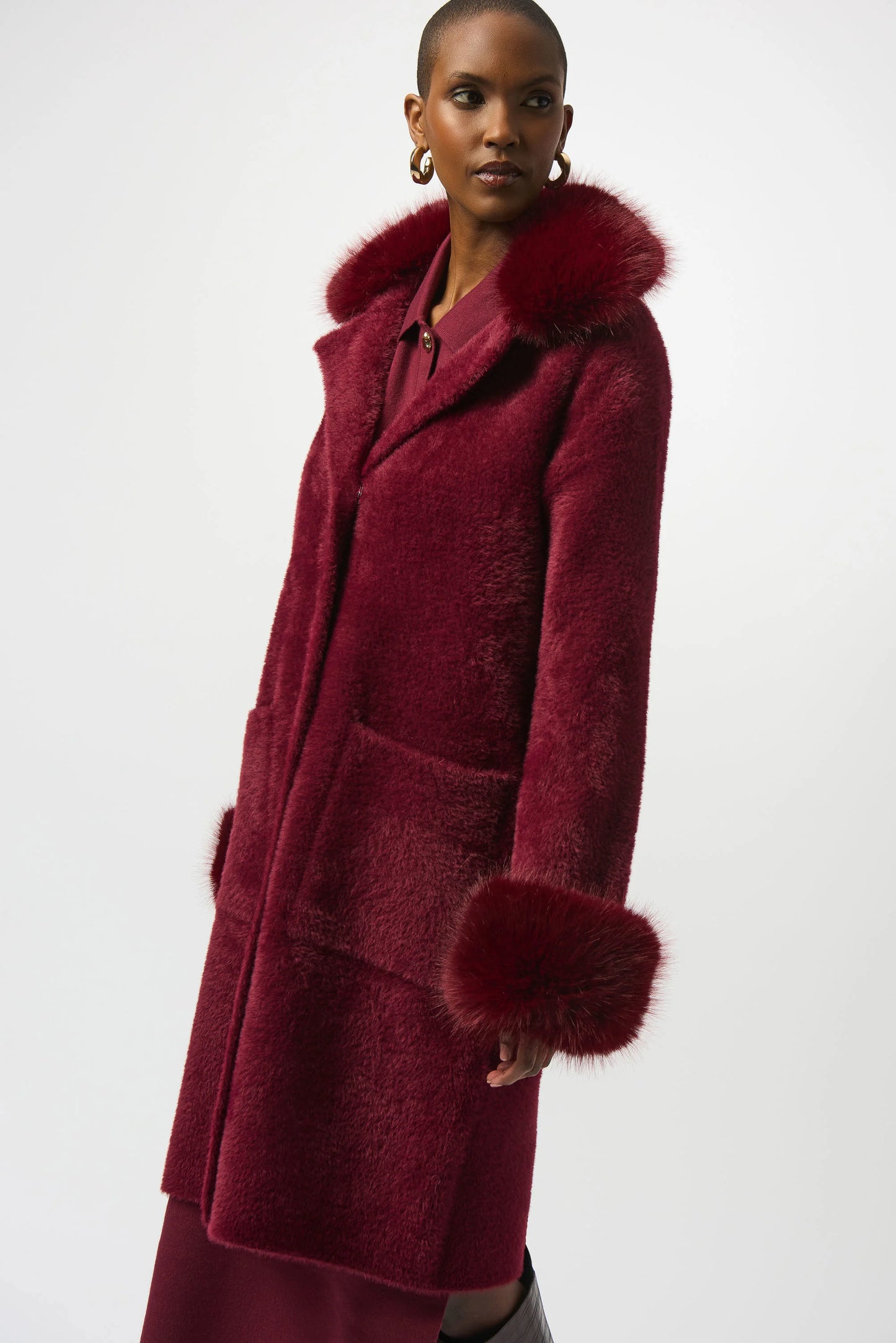 Woman wearing a burgundy coat with fur trim on a white background