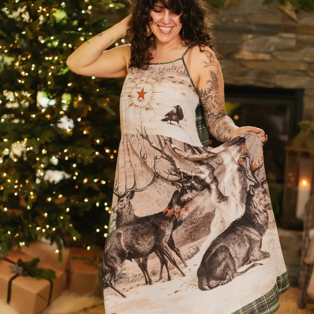 Woman wearing a long dress with nature-themed print in a festive indoor setting.