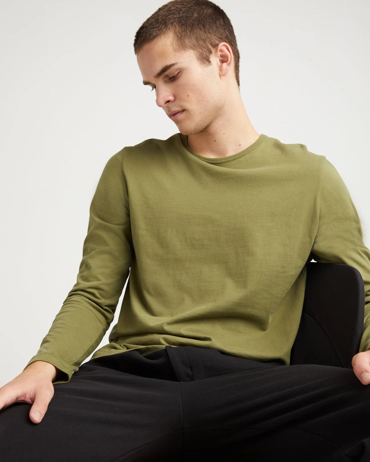 A man wearing the Weighted Organic Cotton Long Sleeve Tee by Richer Poorer in the color Olive Army