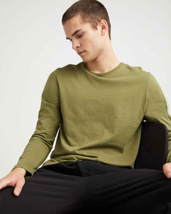 Front view of model wearing a long sleeve green t-shirt