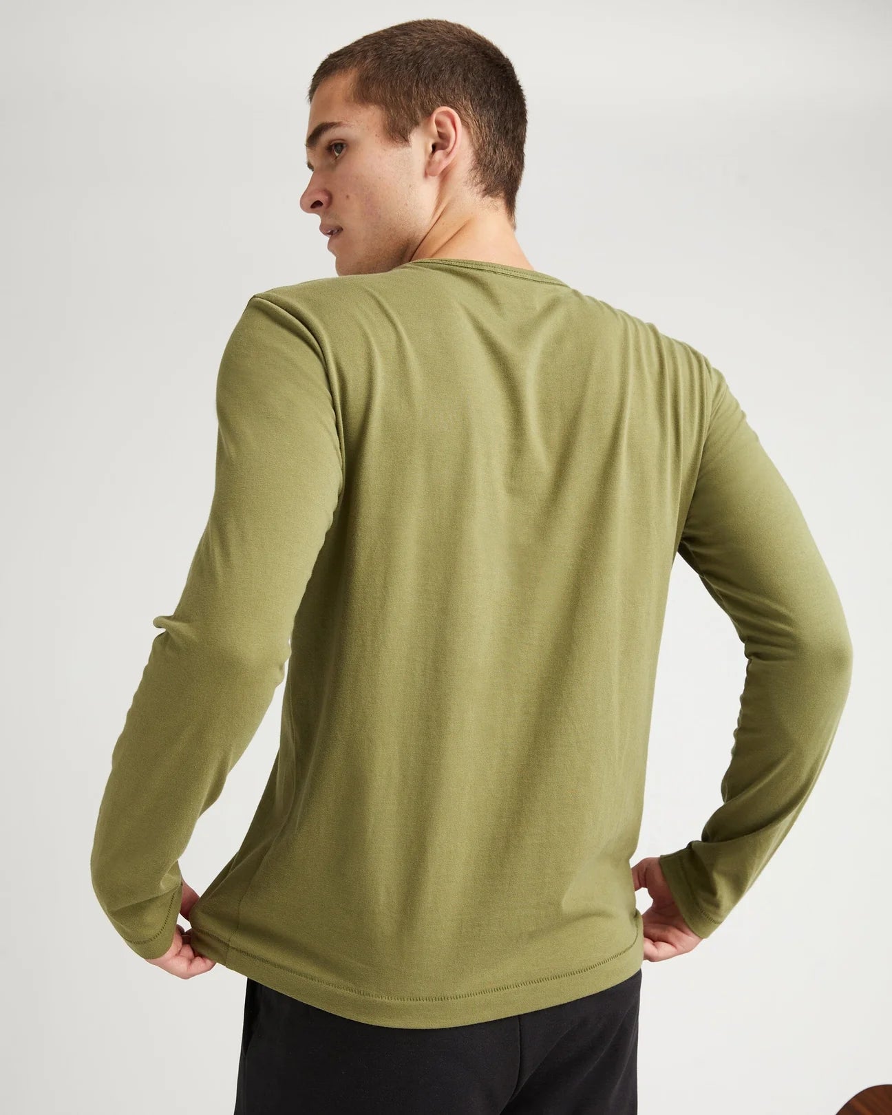 back view of model wearing a long sleeve green t-shirt