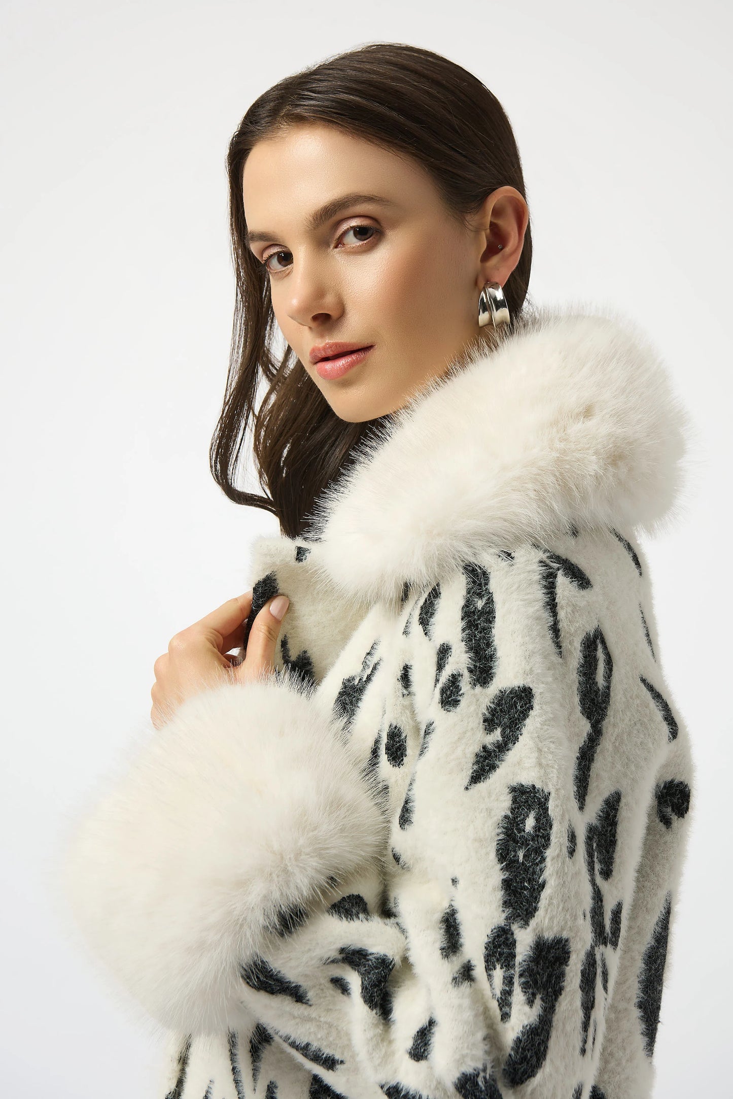 Woman wearing a black and white spotted coat with white faux fur trim
