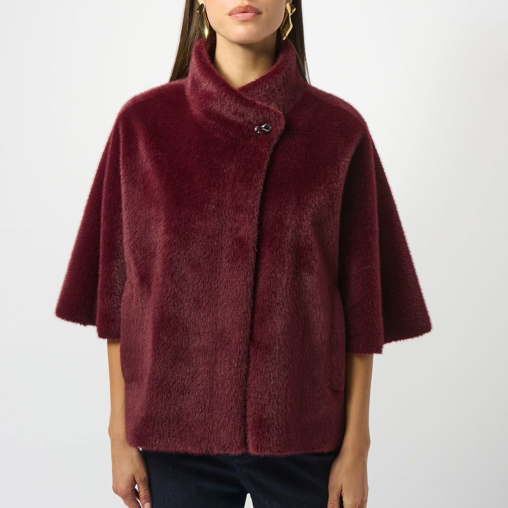 Woman wearing a burgundy mock collar faux fur jacket by Joseph Ribkoff
