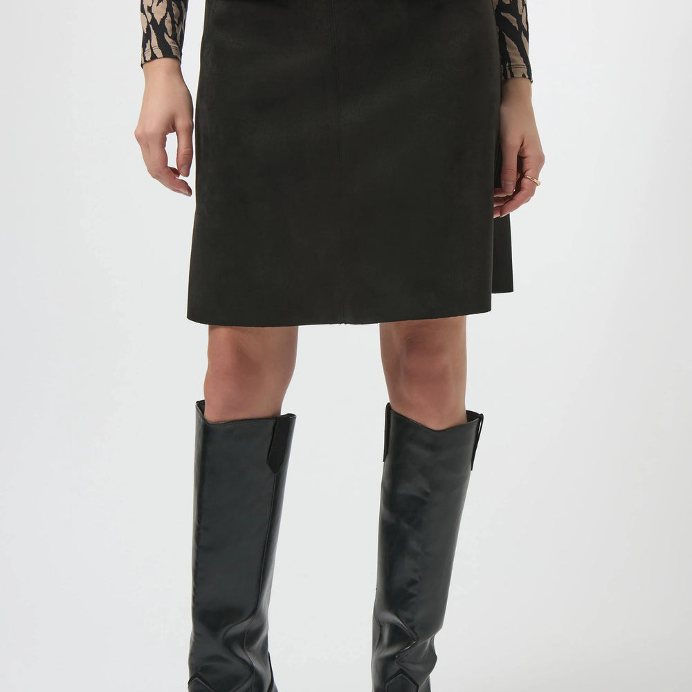 Person wearing a black skirt and black knee-high boots 