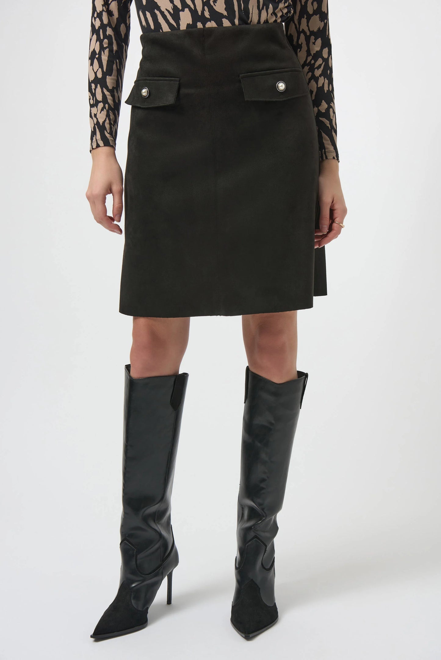 Person wearing a black skirt and black knee-high boots 