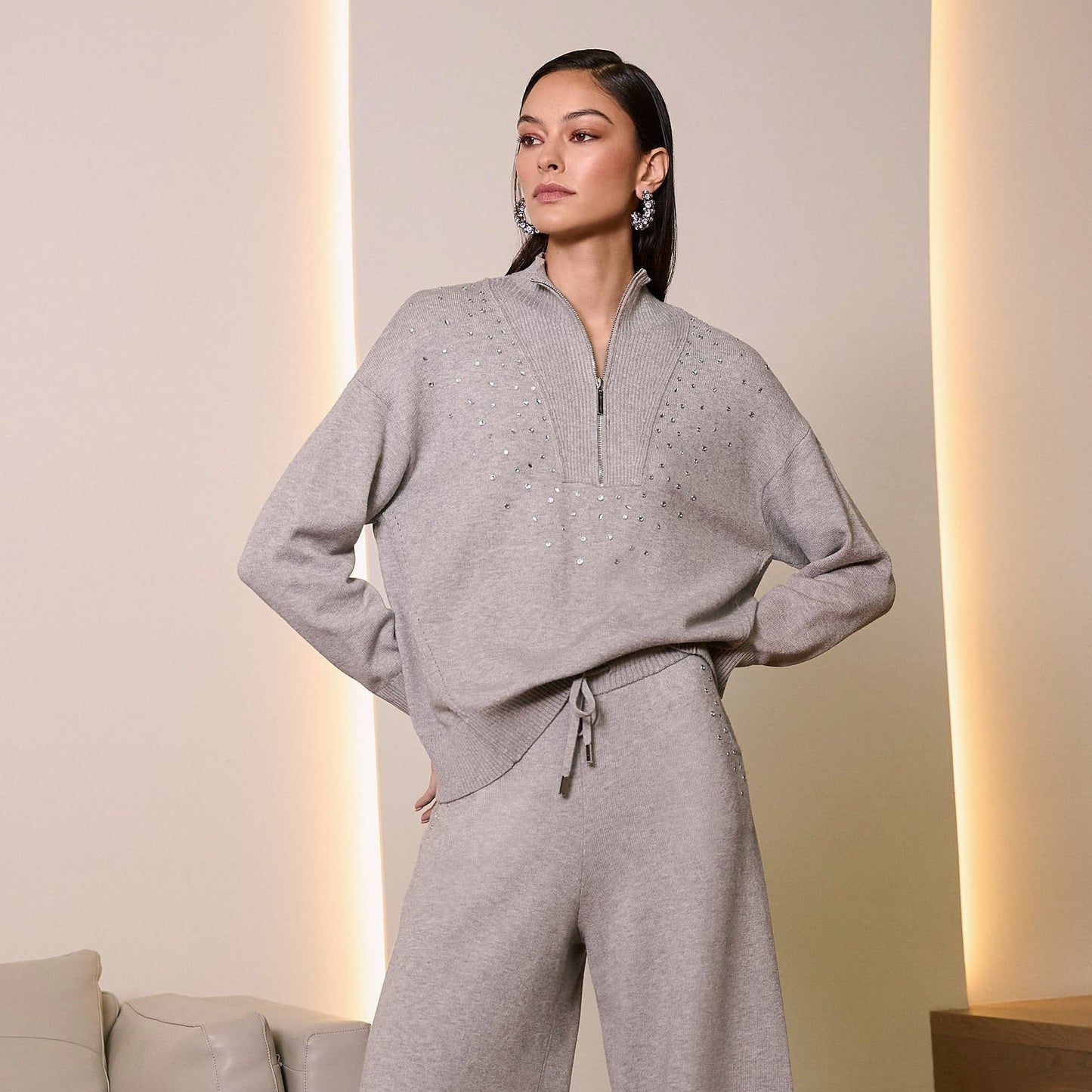 A woman wearing the Joseph Ribkoff Sweater Knit Mock Neck Pullover with Rhinestones paired with matching pants