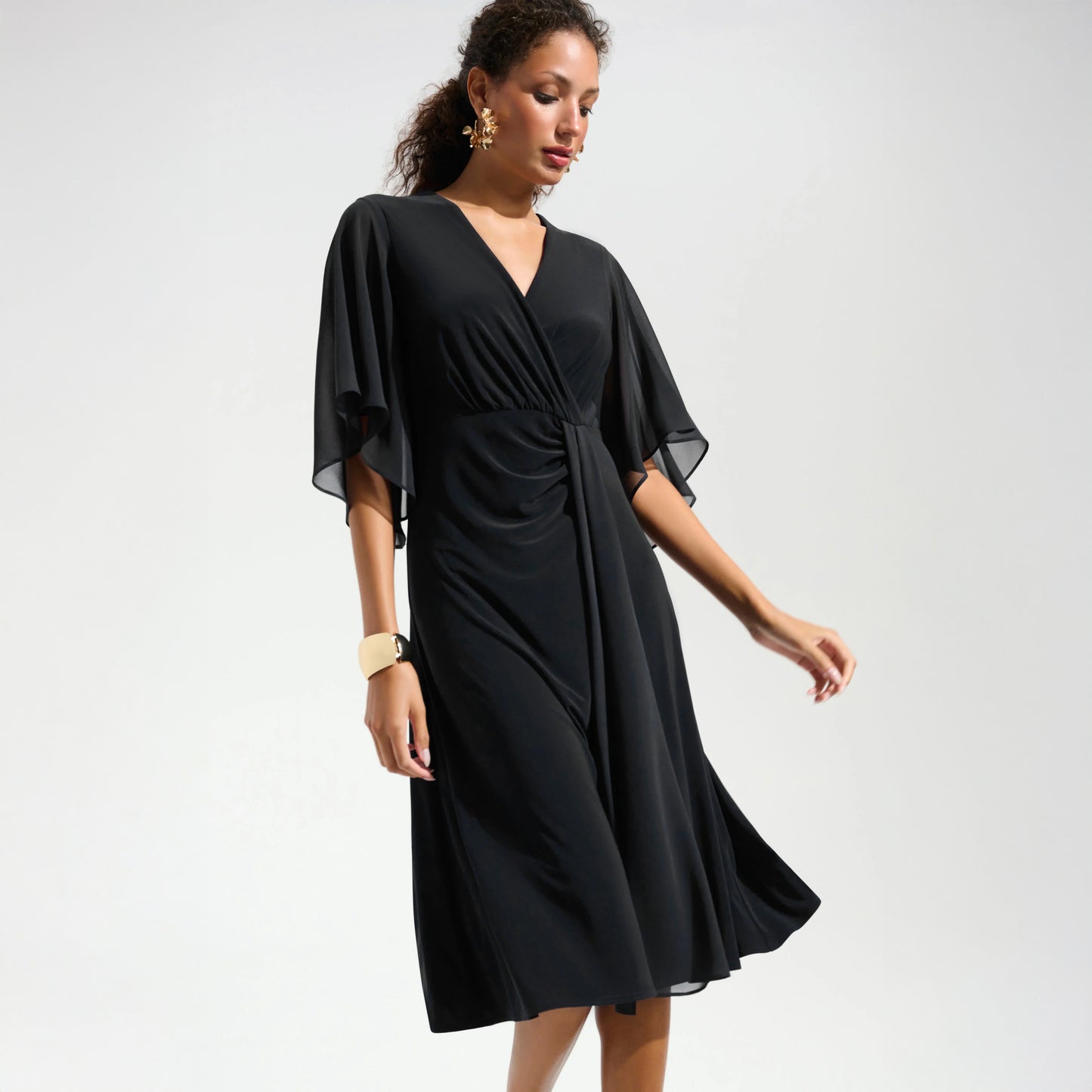 Woman wearing a black dress with sheer sleeves on a white background