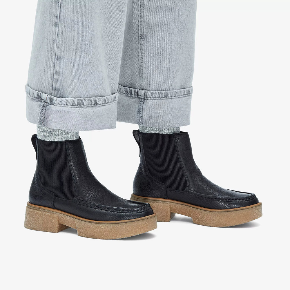 
                      
                        A person wearing the Black Leather Linoso Top Chelsea Boot from the brand Clarks paired with light wash cuffed jeans
                      
                    