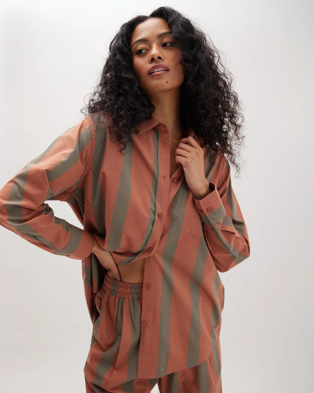 A woman wearing the Venice Button Up Shirt by Richer Poorer in the color Russet Sage Stripe