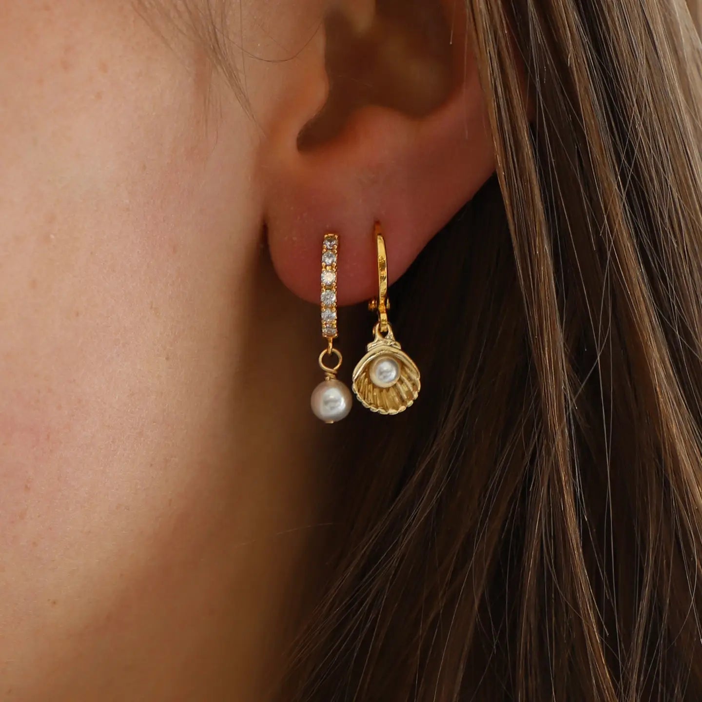 Woman wearing the Shell Huggie Earrings by Katie Waltman Jewelry in her second ear piercing. 
