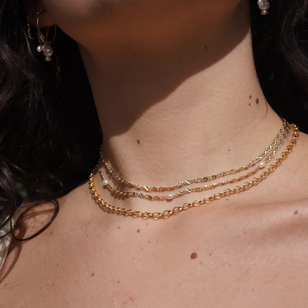 A woman wearing the Sonny Pearl Necklace by May Martin layered with other necklaces