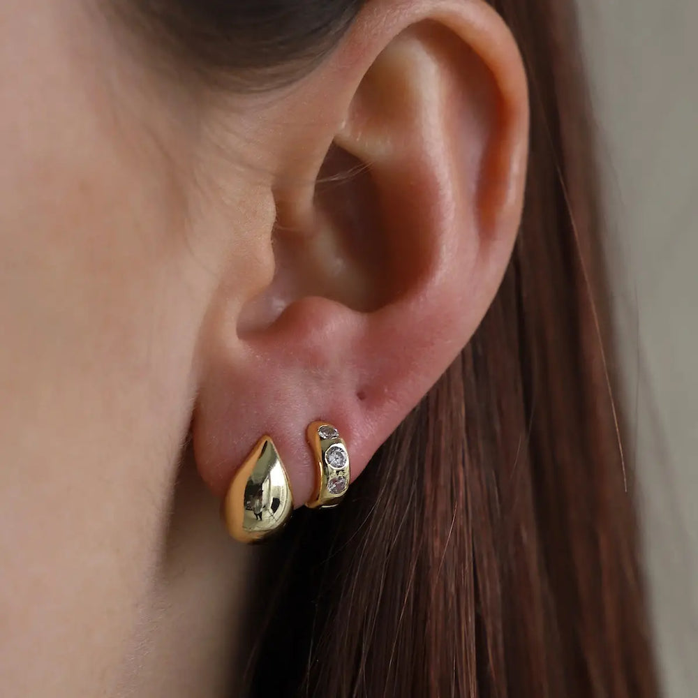 Close-up of an ear wearing gold earrings from Katie Waltman Jewelry