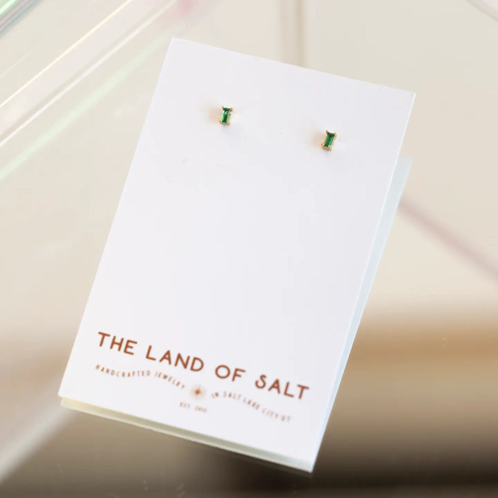 The Dara Emerald CZ Baguette Gold Stud Earrings by The Land Of Salt on their display card