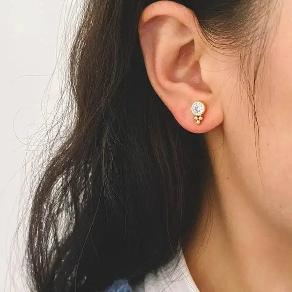 A person wearing the Hana Stud Earrings by the brand Tramps + Thieves