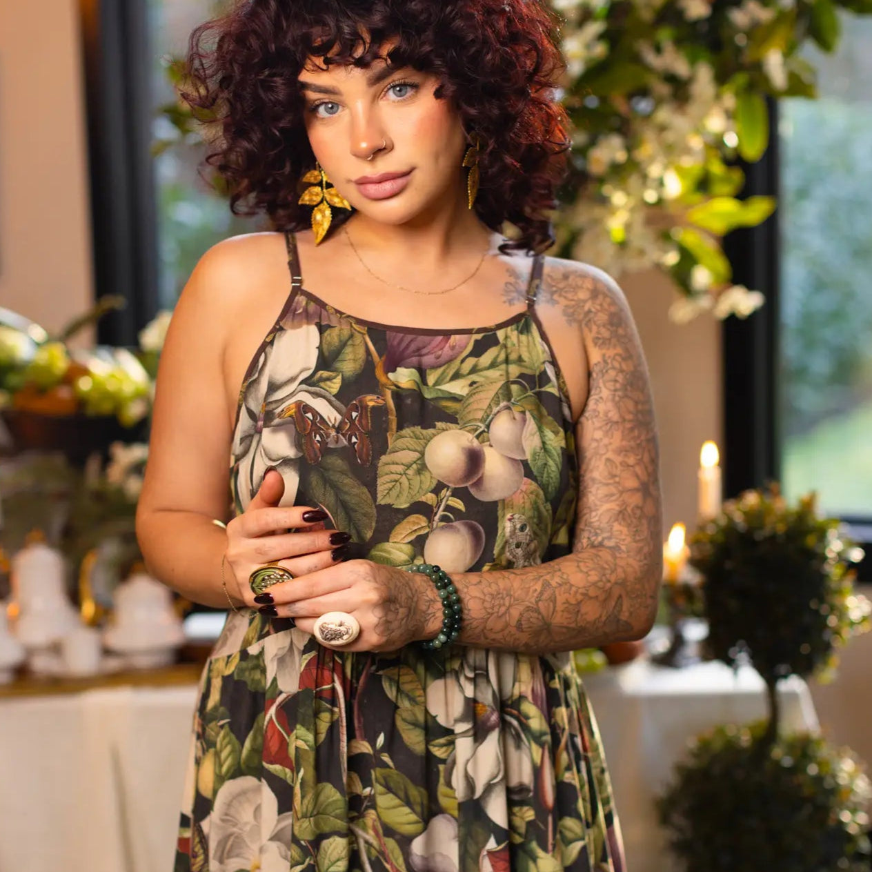 Woman in a floral dress standing in an elegant indoor setting with floral decorations.