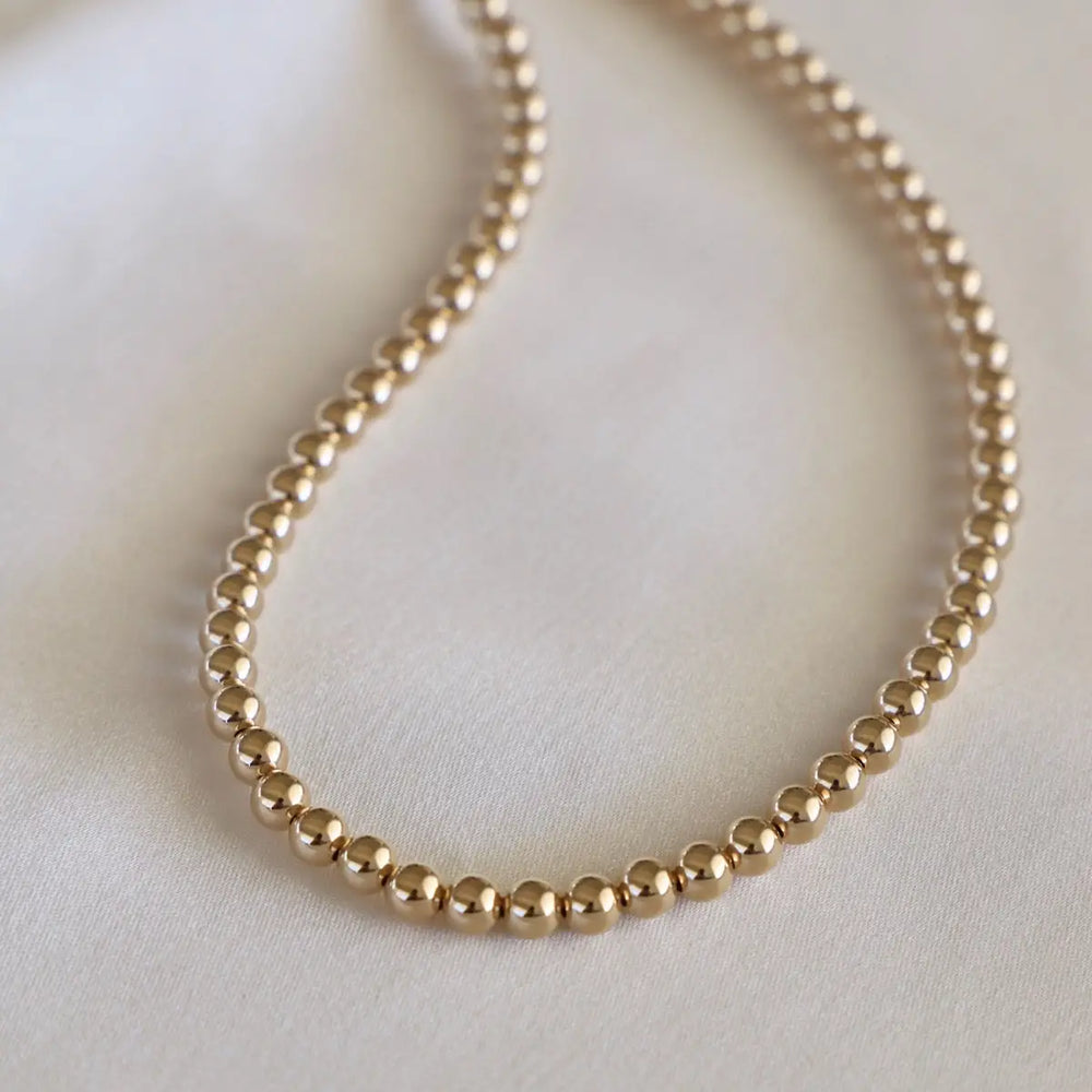 Gold beaded necklace on a light background