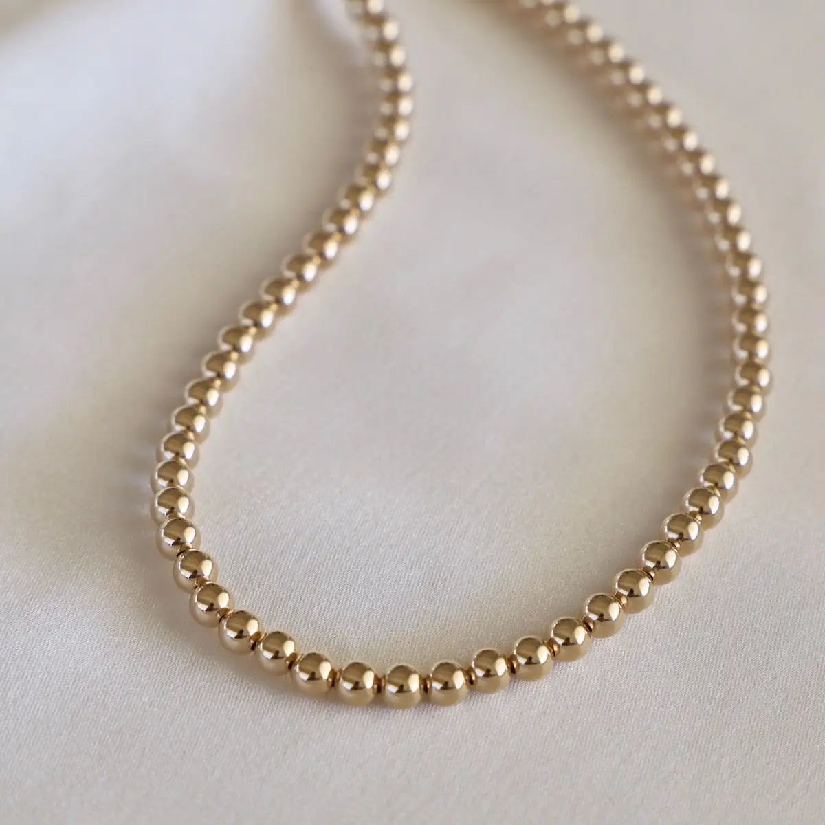 Gold beaded necklace on a light background