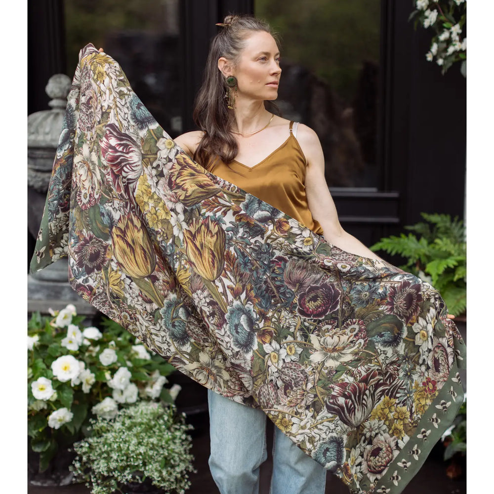 A woman holding the Love Grows Wild Floral Bamboo Scarf with Bees by Market of Stars