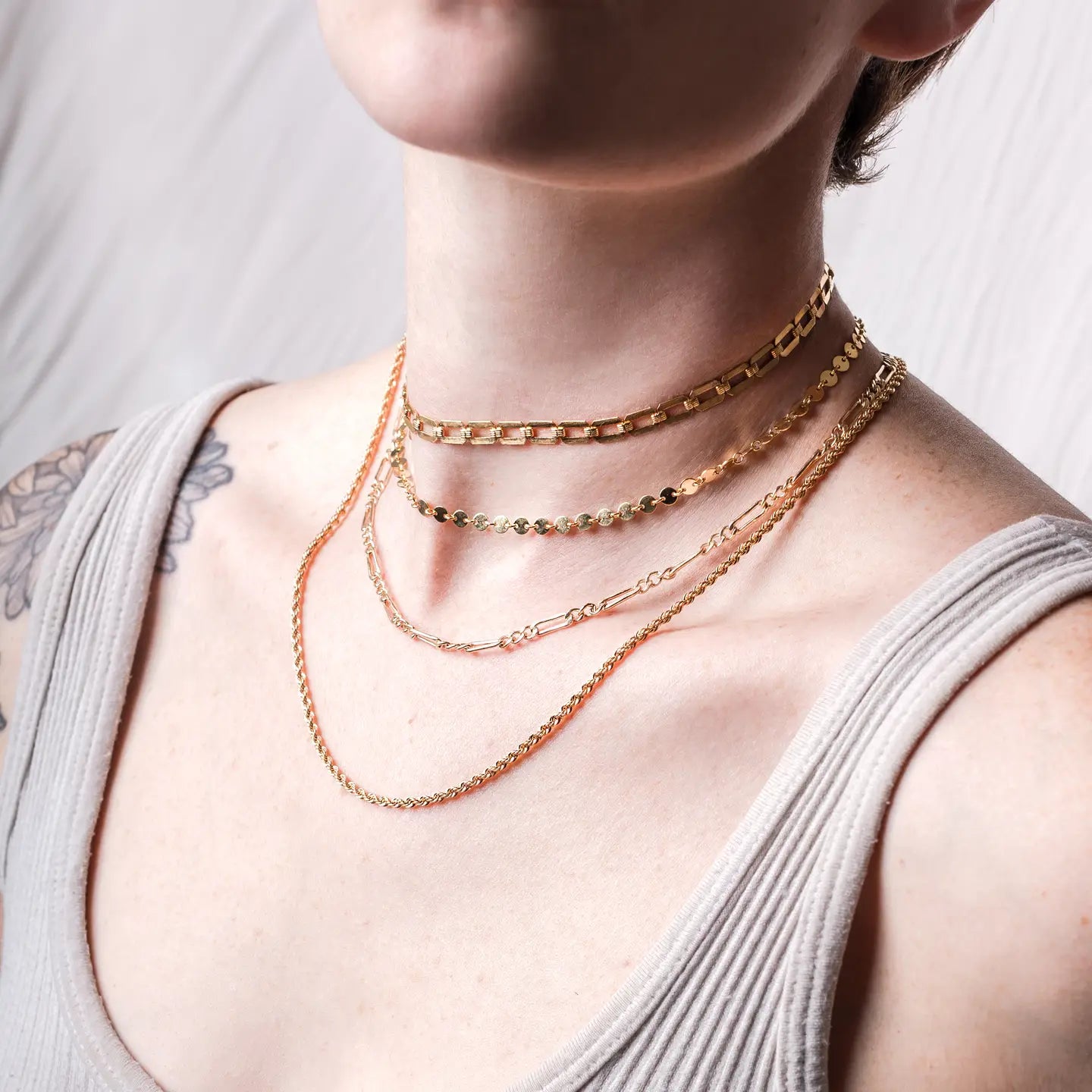 A person wearing the Circle Disc Chain Goldfill Necklace by Mineral and Matter layered with several other necklaces