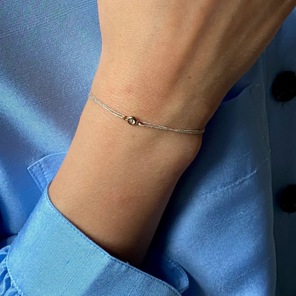 Person wearing a bracelet on lurex thread, small zirconium set in 3 micron gold plated.