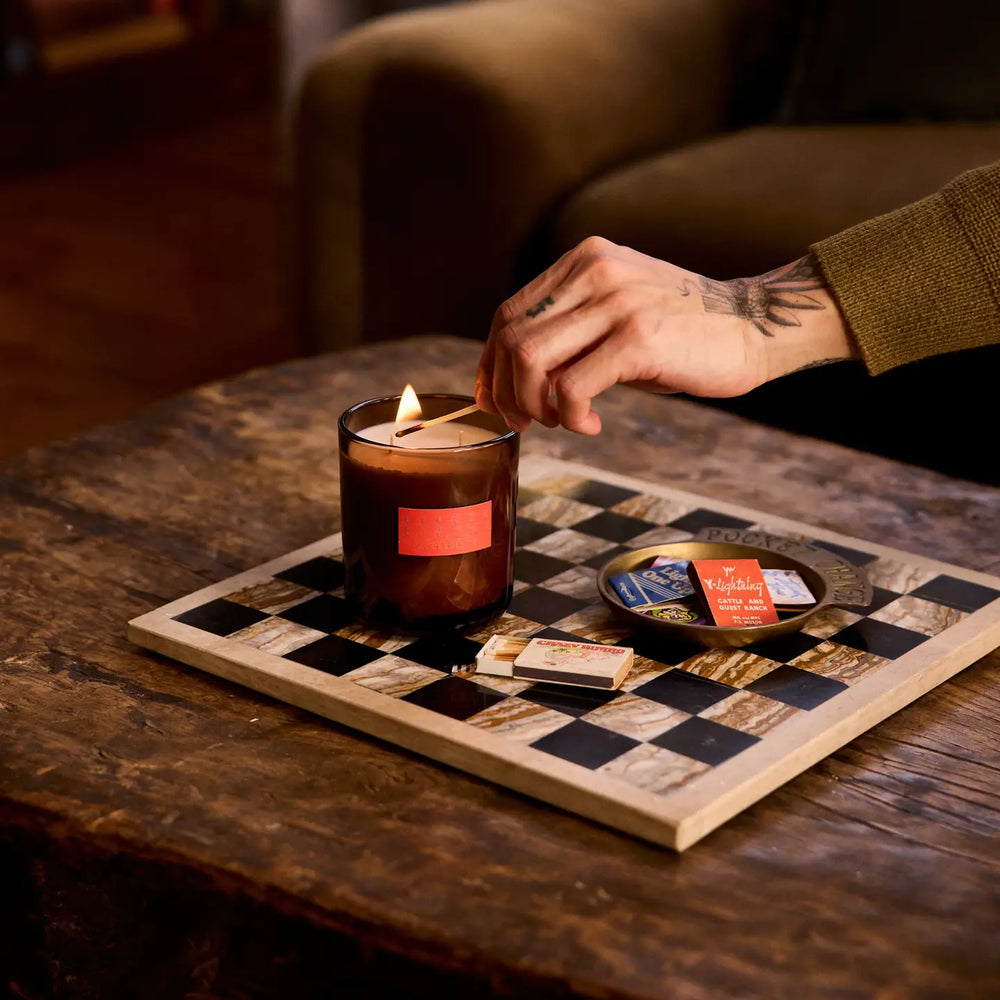 A person lighting a double wick candle in a low-lit atmosphere