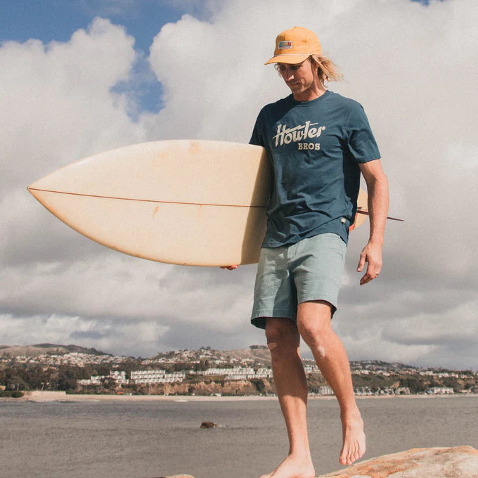 
                      
                        Front view of man wearing a blue Howler Bros short sleeve men's t-shirt at the beach
                      
                    