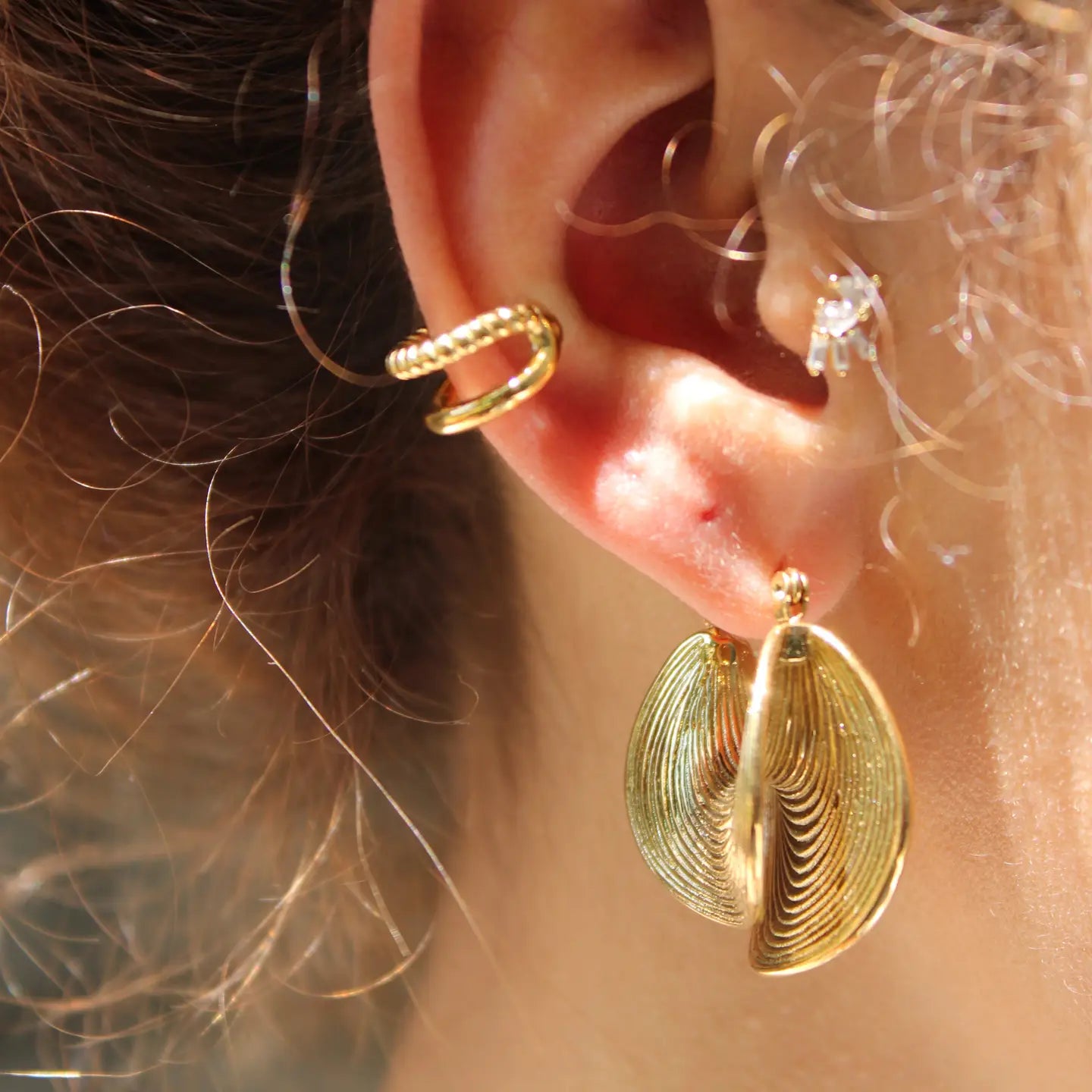 Close-up of an ear wearing gold earrings 