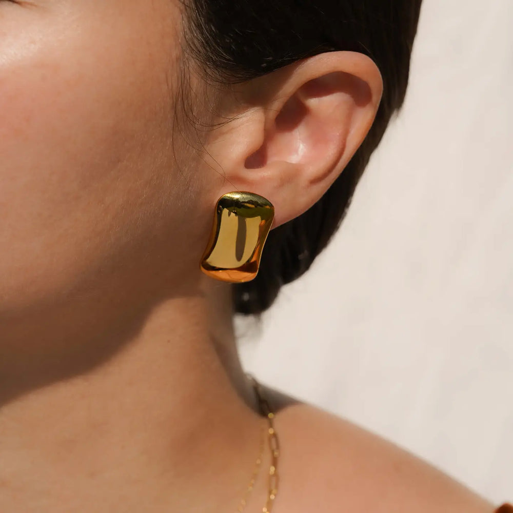 Person wearing gold earrings by KOZAKH