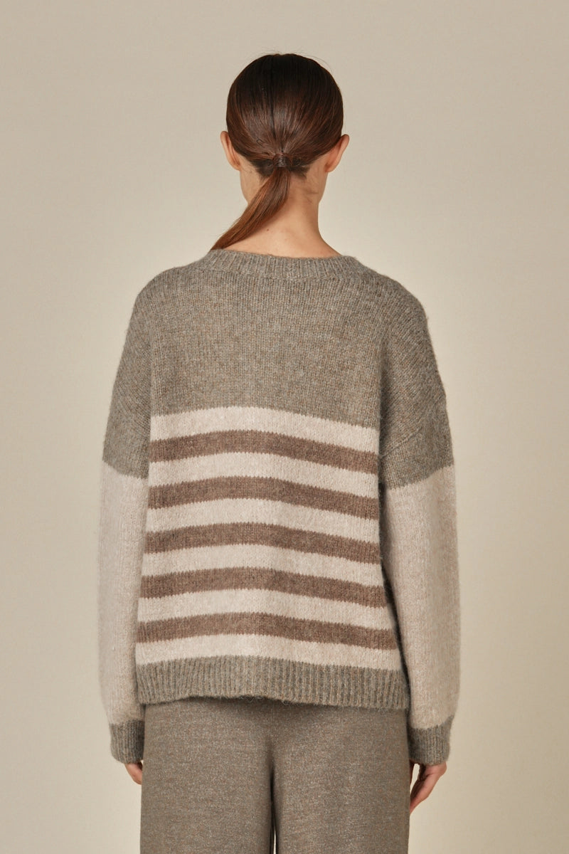 Back view of a woman wearing a grey, brown and beige colorblock striped cardigan