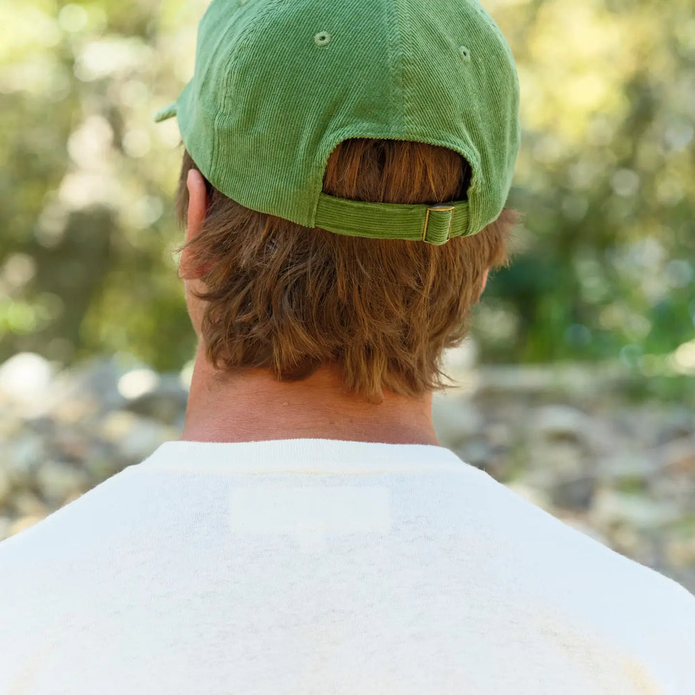 
                      
                        Person wearing a green cap with adjustable back closure
                      
                    