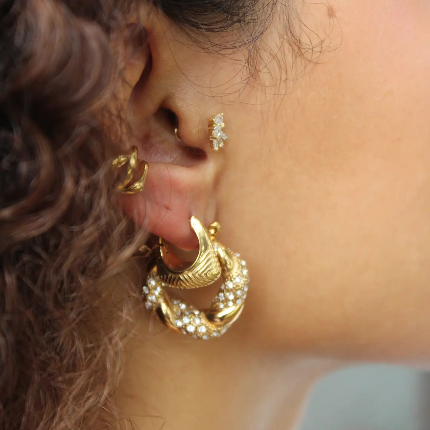 Close-up of an ear wearing gold hoop earrings 