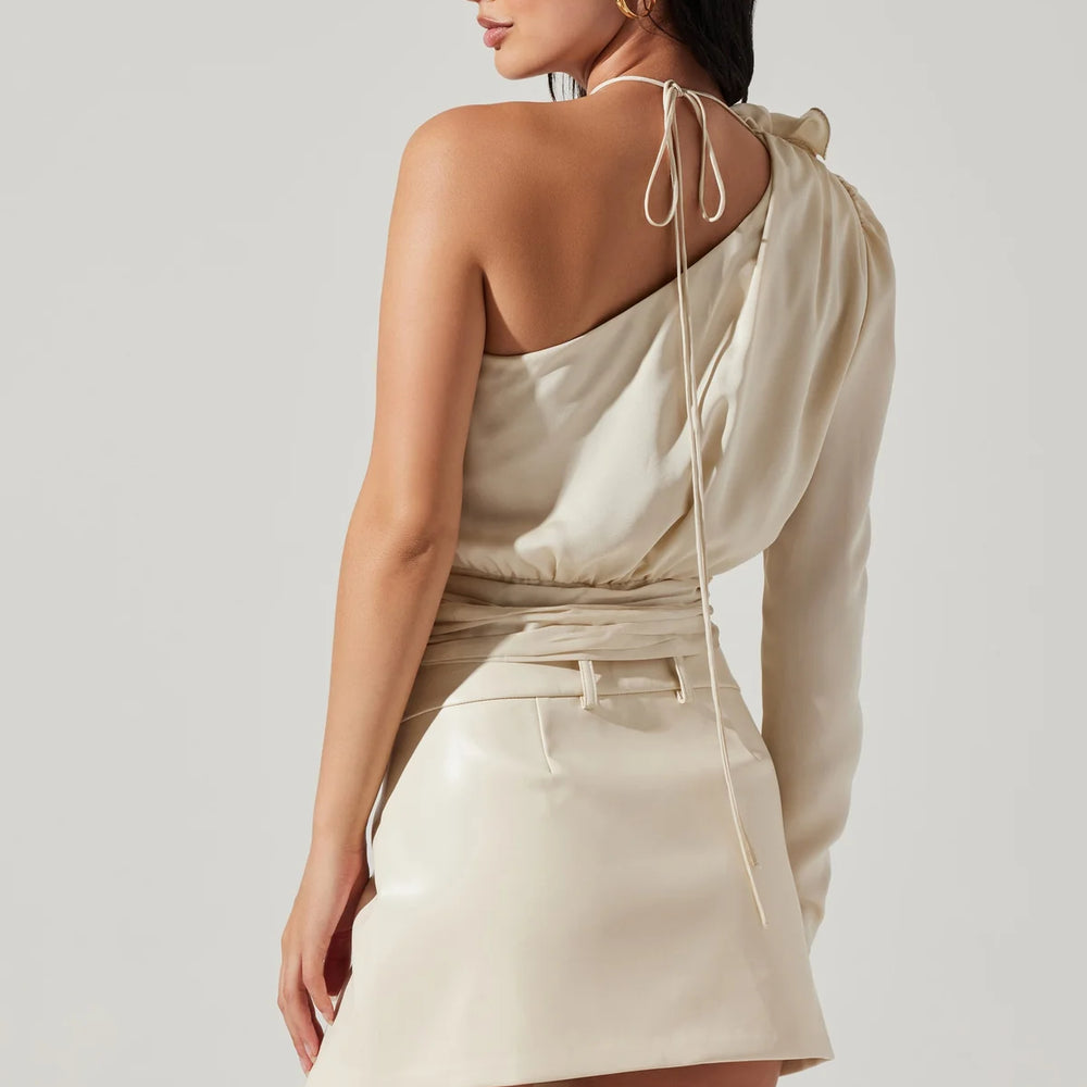 
                      
                        Back  view of woman wearing a champagne color satin one shoulder long sleeve top with a corsage detail at the top shoulder
                      
                    