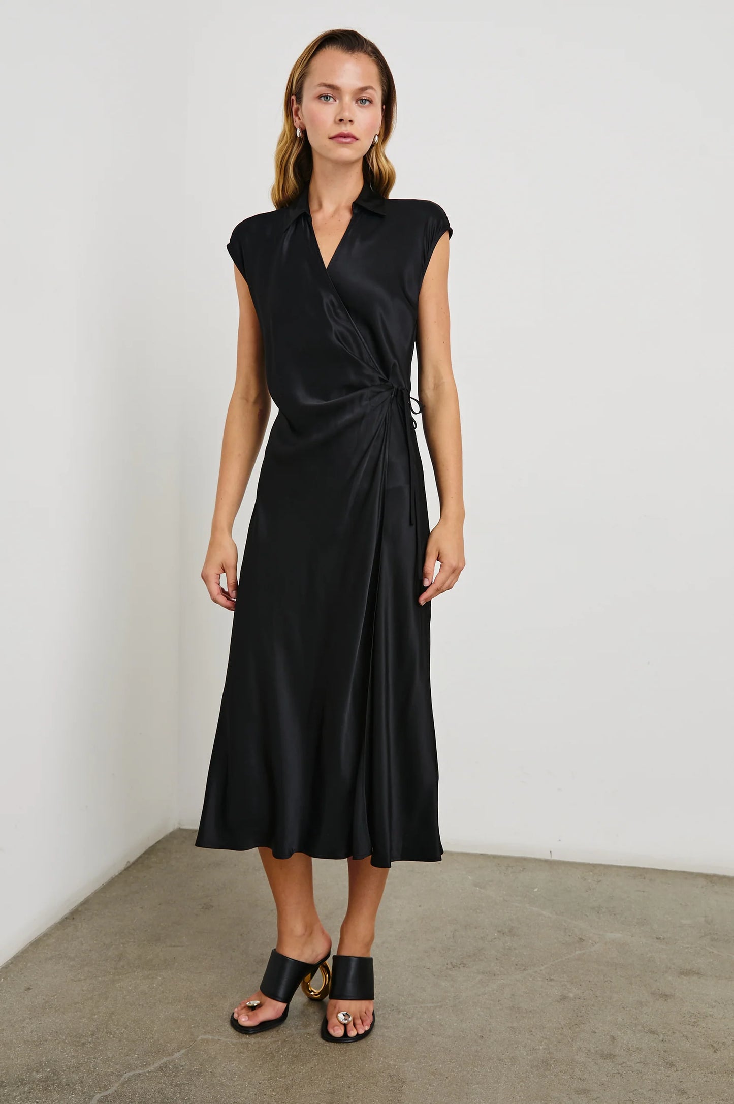 A woman wearing the black Alai wrap midi dress by the brand Rails