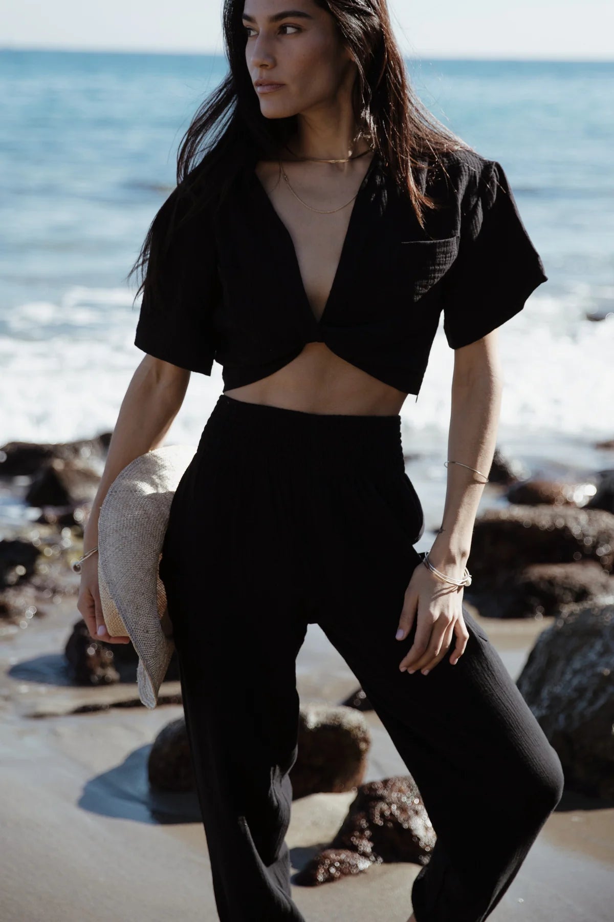 Woman at the beach wearing Stillwater's Knot Front Short Sleeve Shirt in the color Black